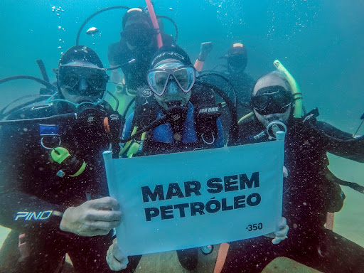 A group of divers holding up a sign against ocean drilling