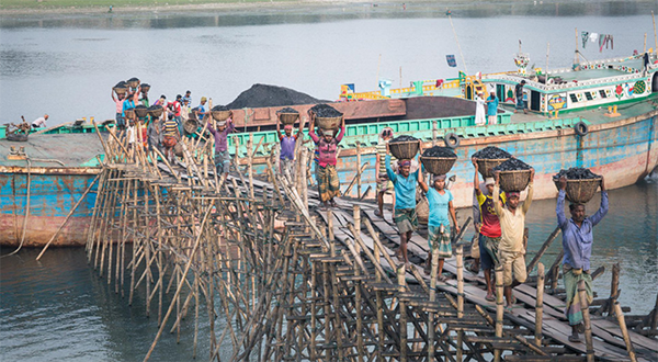 People unload baskets of coal out of a boat in Bangladesh